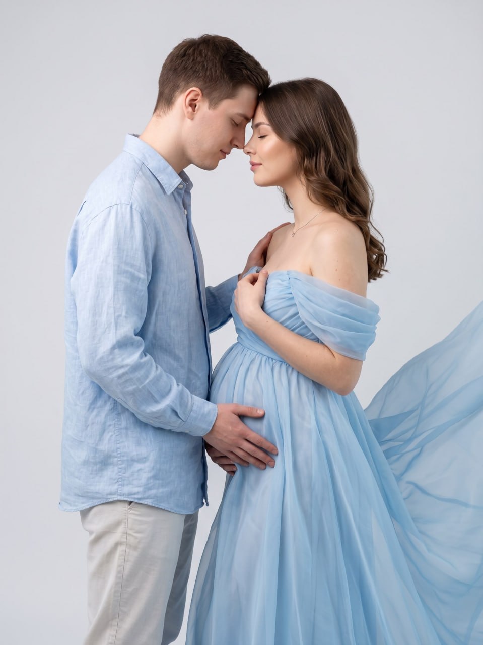 ИИ-фотосессия по фото: беременная пара в нежно-голубых нарядах соприкасается лбами на чистом светлом фоне в студии.