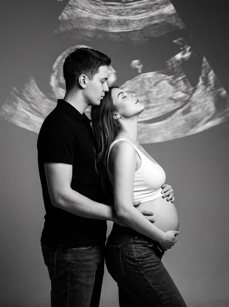 ИИ-фотосессия по фото: будущие родители в профиль в студии на фоне проекции снимка УЗИ, мужчина обнимает беременную женщину.