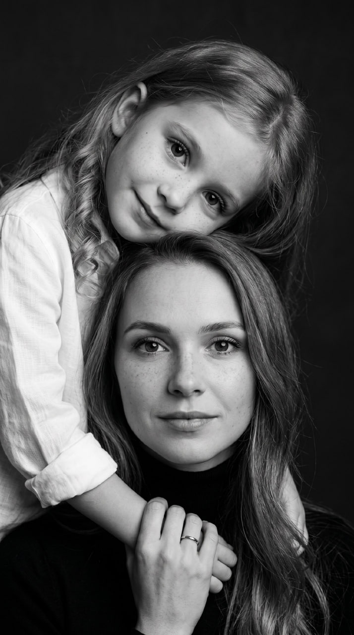 ИИ-фотосессия по фото: черно-белый студийный портрет мамы и дочки в нежных объятиях крупным планом на темном фоне.