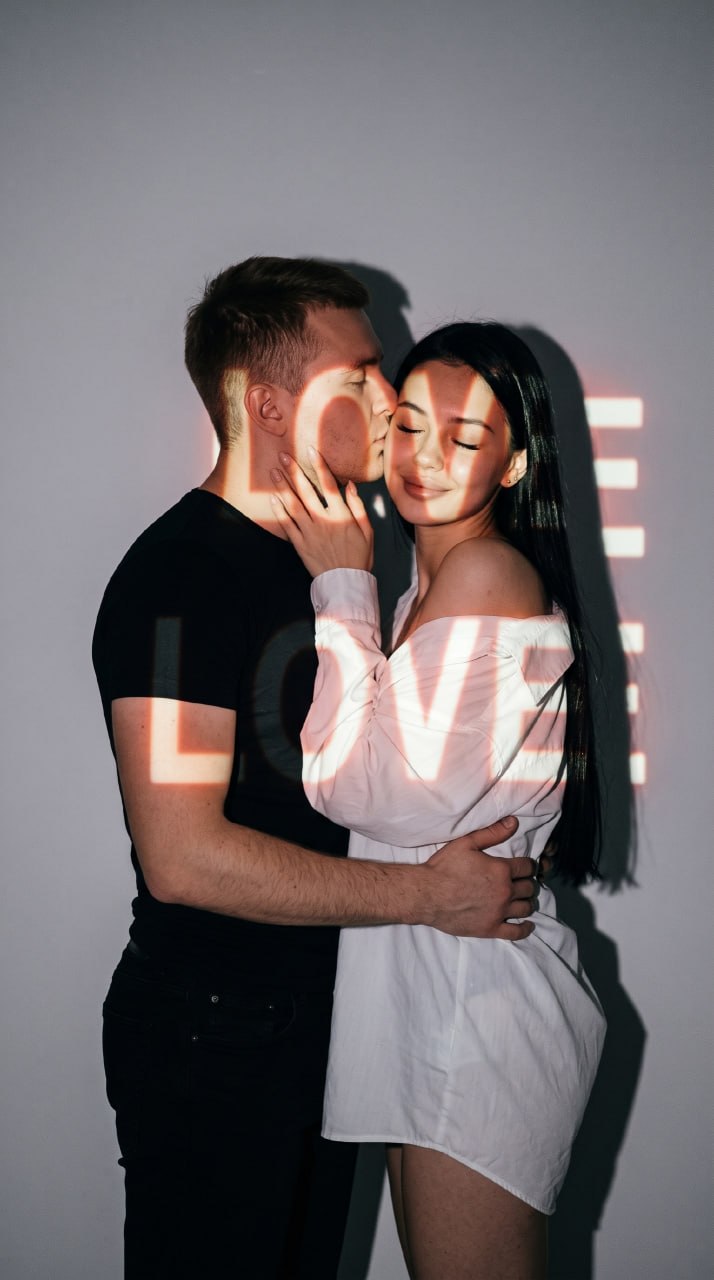ИИ-фотосессия по фото: обнимающаяся пара на фоне серой стены с красной проекционной надписью LOVE